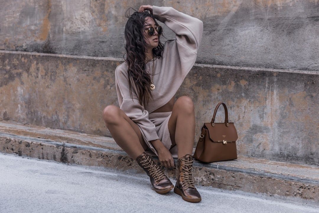 Kvinna i monokrom beige outfit med boots och brun handväska